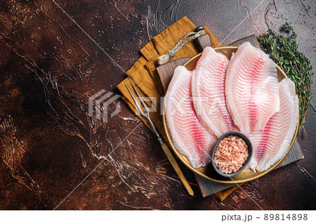 Raw fish fillet of tilapia in a plate with spices. Dark background. Top view. Copy space 89814898