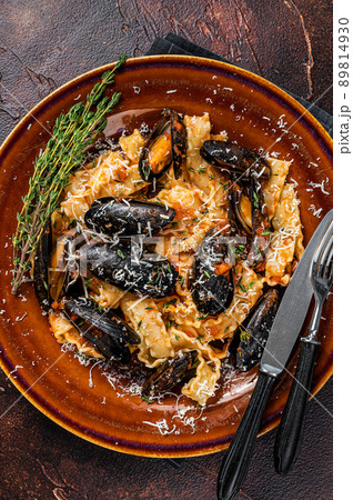 Seafood Mafaldine pasta with mussels and tomato sauce in a rustic plate. Dark background. Top view 89814930