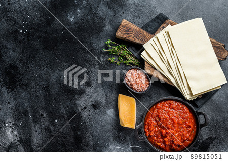 Raw Different ingredients for cooking Italian lasagna on a kitchen table. Black background. Top view. Copy space Raw Different ingredients for cooking Italian lasagna on a kitchen table. Black background. Top view. Copy space 89815051