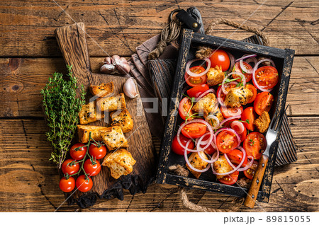 Traditional Italian Panzanella salad with tomatoes, onion and bread Croutons in wooden tray. Wooden background. Top view Traditional Italian Panzanella salad with tomatoes, onion and bread Croutons in wooden tray. Wooden background. Top view 89815055
