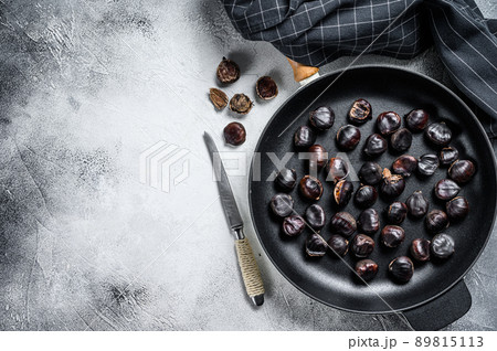 Roast chestnuts in a pan on a wooden table. White background. Top view. Copy space Roast chestnuts in a pan on a wooden table. White background. Top view. Copy space 89815113