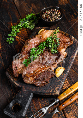 Grilled Chuck eye roll beef meat steak on a cutting board. Dark wooden background. Top view Grilled Chuck eye roll beef meat steak on a cutting board. Dark wooden background. Top view 89815186