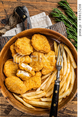 Crispy fried Chicken nuggets with French fries in wooden plate. Wooden background. Top view Crispy fried Chicken nuggets with French fries in wooden plate. Wooden background. Top view 89815208