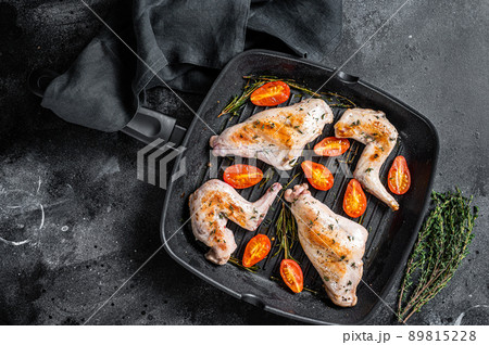 Roasted rabbit legs in a pan with thyme. Black background. Top view 89815228