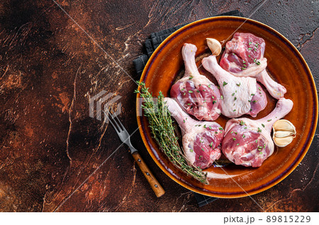 Raw Poultry meat - Duck legs drumsticks on a rustic plate with herbs. Dark background. Top view. Copy space Raw Poultry meat - Duck legs drumsticks on a rustic plate with herbs. Dark background. Top view. Copy space 89815229