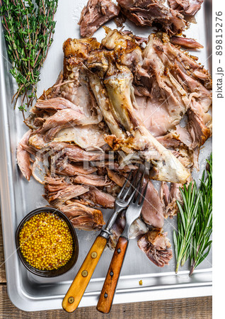 Baked pork knuckle eisbein meat on a baking pan with herbs. Wooden background. Top view 89815276