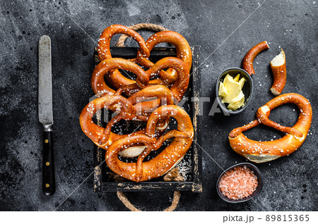 Bavarian baked Salted pretzels in a wooden tray. Black background. Top view 89815365