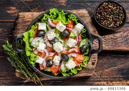 Greek salad with fresh vegetables and feta cheese in a pan. Dark Wooden background. Top view 89815366