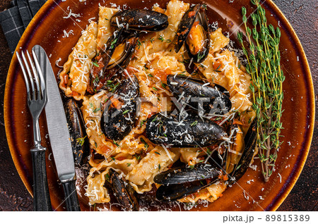 Seafood Mafaldine pasta with mussels and tomato sauce in a rustic plate. Dark background. Top view Seafood Mafaldine pasta with mussels and tomato sauce in a rustic plate. Dark background. Top view 89815389