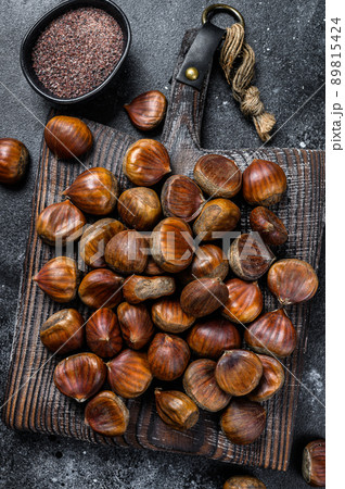 Raw chestnuts on a wooden cutting board. Black background. Top view 89815424