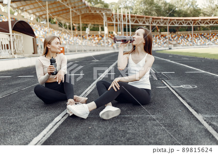 Beautiful girls at the stadium. Sports girls in a sportswear. People with bottle of water. Beautiful girls at the stadium. Sports girls in a sportswear. People with bottle of water. 89815624