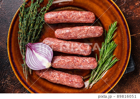 Raw kofta meat kebabs sausages on a plate with herbs. Dark background. Top view 89816051