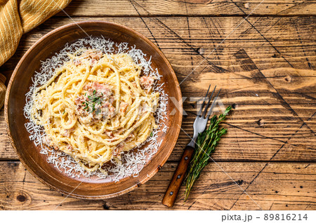 Spaghetti Carbonara pasta with pancetta, egg, hard parmesan cheese and cream sauce. Wooden background. top view. Copy space 89816214