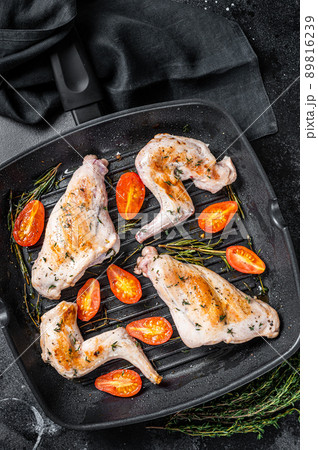 Roasted rabbit legs in a pan with thyme. Black background. Top view 89816239