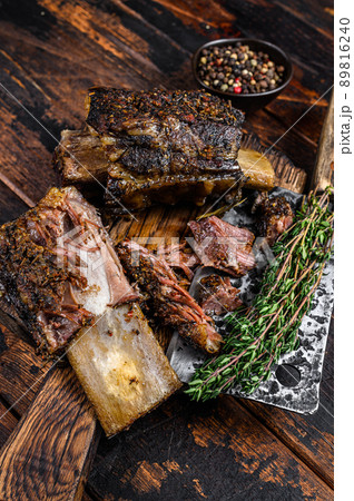 BBQ short chuck beef ribs with herbs and meat cleaver. Dark wooden background. Top view 89816240