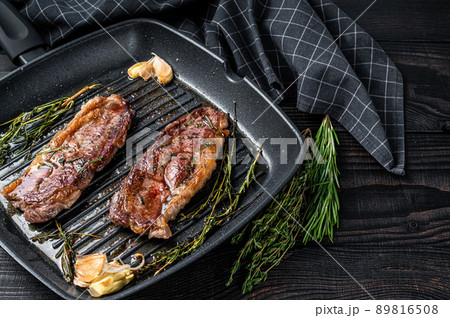 Grilled Prime Black Angus beef steaks Striploin or New York in a grill pan. Dark wooden background. Top view. Copy space 89816508