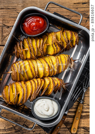 Skewered fried tornado or twist potatoes with ketchup sauce. Wooden background. Top view Skewered fried tornado or twist potatoes with ketchup sauce. Wooden background. Top view 89816607