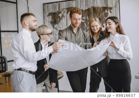 People are working on the project. Men and women in suits sitting at the table. Businesspeople looking at blueprints. 89816637