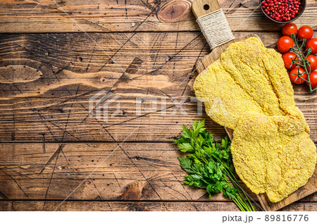 Italian raw Milanese schnitzel. Wooden background. Top view. Copy space Italian raw Milanese schnitzel. Wooden background. Top view. Copy space 89816776