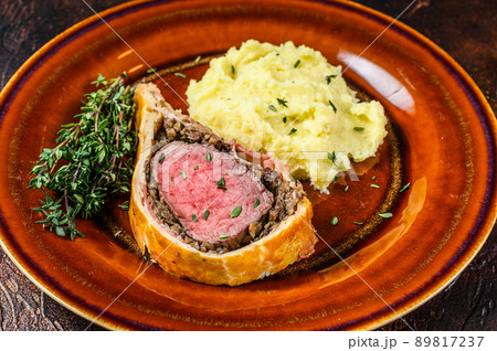 Beef Wellington pastry with mushed potato on a rustic plate. Dark background. Top view Beef Wellington pastry with mushed potato on a rustic plate. Dark background. Top view 89817237