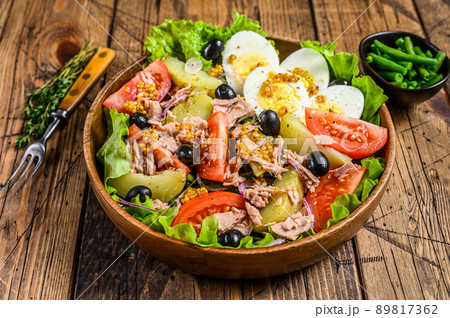 Nicoise salad with tuna, tomatoes, olives, green beans, cucumber, soft boiled eggs and potato in a wooden bowl. wooden background. top view Nicoise salad with tuna, tomatoes, olives, green beans, cucumber, soft boiled eggs and potato in a wooden bowl. wooden background. top view 89817362