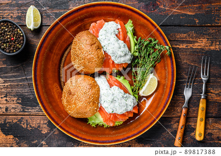 Fishburger with salted fish salmon, avocado, burger bun, mustard sauce and Iceberg salad. Dark wooden background. top view 89817388