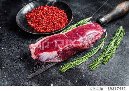 Raw marbled beef meat strip loin steak on a knife. Black background. Top view 89817432