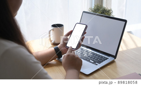 Woman sitting in bright living room and using mobile phone, checking social media 89818058