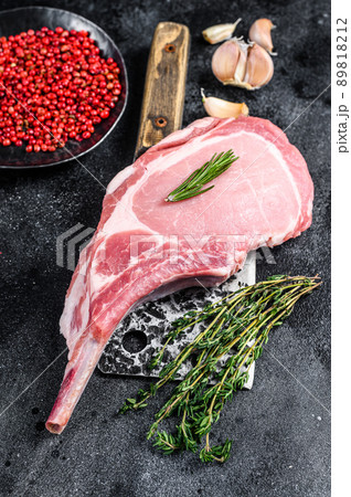 Raw tomahawk pork chop meat steak on a meat cleaver. Black background. Top view 89818212