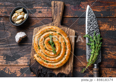 BBQ spiral sausage from pork and beef meat on a wooden cutting board. Dark wooden background. Top view 89818374