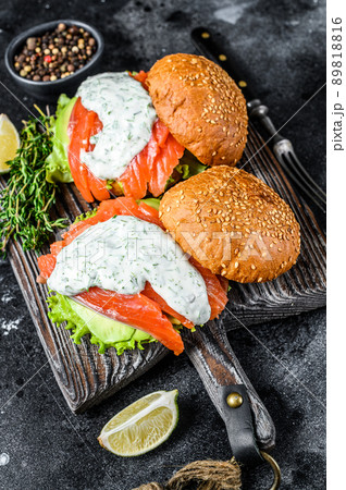Fish burger with salted salmon, avocado, mustard sauce, cucumber and Iceberg salad. Black background. top view 89818816