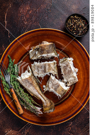 Baked cod white fish in a plate. Dark wooden background. Top view 89819084