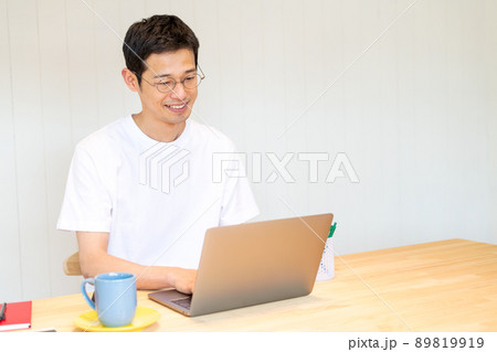 マグカップとソーサーを傍に置きながらPC作業をする男性 マグカップとソーサーを傍に置きながらPC作業をする男性 89819919