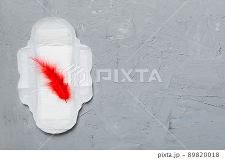 Women hygiene products or Sanitary pad with red feather on colored background. Pastel color. Closeup. Empty place for text. Female daily hygiene 89820018