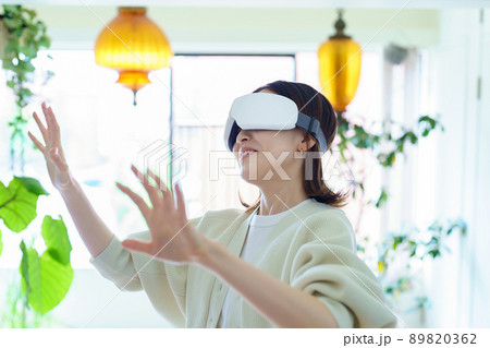 部屋でVRゴーグルを装着して、手探りをする女性 89820362