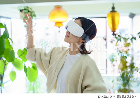 部屋でVRゴーグルを装着して、手探りをする女性 部屋でVRゴーグルを装着して、手探りをする女性 89820367