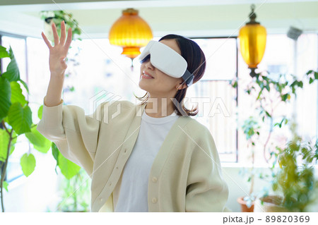 部屋でVRゴーグルを装着して、手探りをする女性 部屋でVRゴーグルを装着して、手探りをする女性 89820369