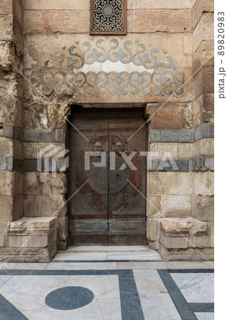 Stone bricks wall and wooden decorated copper plated door at Sultan Barquq mosque, Cairo, Egypt Stone bricks wall and wooden decorated copper plated door at Sultan Barquq mosque, Cairo, Egypt 89820983