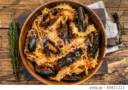 Mussels and clams Mafaldine pasta with tomato sauce in a rustic wooden plate. Wooden background. Top view 89821222