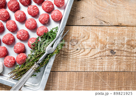 Recipe for cooking meatballs from ground beef with thyme and rosemary in kitchen tray. Wooden background. Top view. Copy space 89821925