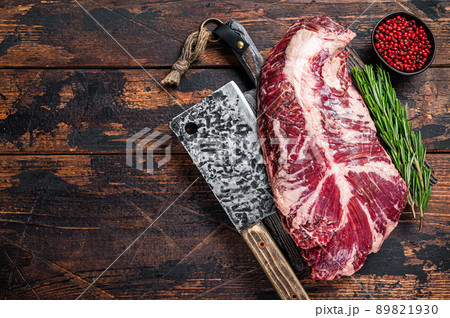 Hanging tender or hanger raw beef meat steak on butcher board with cleaver. Dark wooden background. Top View. Copy space 89821930