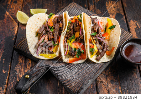 Tacos shells with pork meat, onion, tomato, sweet pepper and salsa. Mexican food. Dark wooden background. Top view Tacos shells with pork meat, onion, tomato, sweet pepper and salsa. Mexican food. Dark wooden background. Top view 89821934