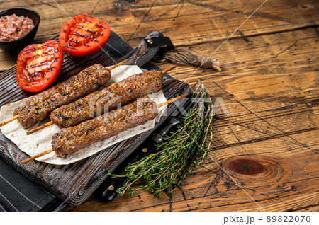 Roasted Turkish Adana shish kebab on a board with grilled tomato. Wooden background. top view. Copy space 89822070