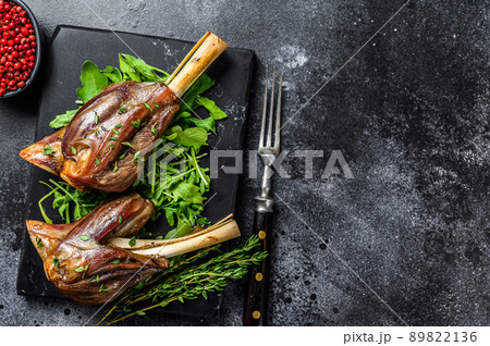 Stew goat Shanks on a marble board with arugula. Black background. Top view. Copy space 89822136