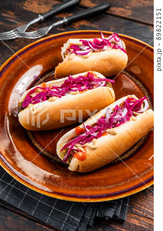 Street food - Vegan hot-dogs with cabbage and meatless sausage. Dark Wooden background. Top view Street food - Vegan hot-dogs with cabbage and meatless sausage. Dark Wooden background. Top view 89822151