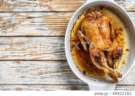Baked whole farm duck in a baking dish. White wooden background. Top view. Space for text Baked whole farm duck in a baking dish. White wooden background. Top view. Space for text 89822162