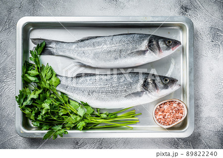 Raw sea bass or seabass fish in a baking dish. White background. Top view 89822240