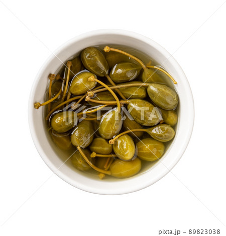 Pickled caper berries in a white bowl isolated on white background. Pickled caper berries in a white bowl isolated on white background. 89823038