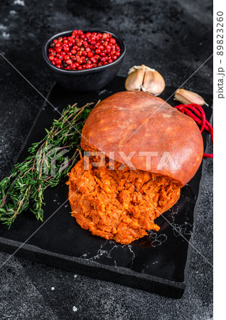 Balearic Sobrassada cured meat sausage from ground pork, paprika and spices. Black background. Top view 89823260