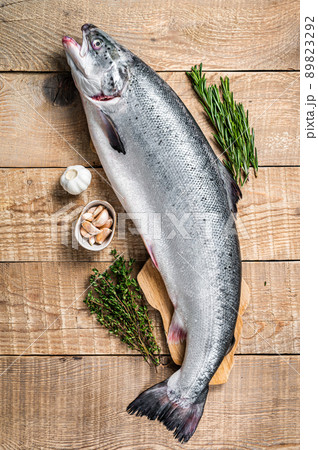 Raw marine salmon fish on a wooden kichen table with herbs. Wooden background. Top view 89823292